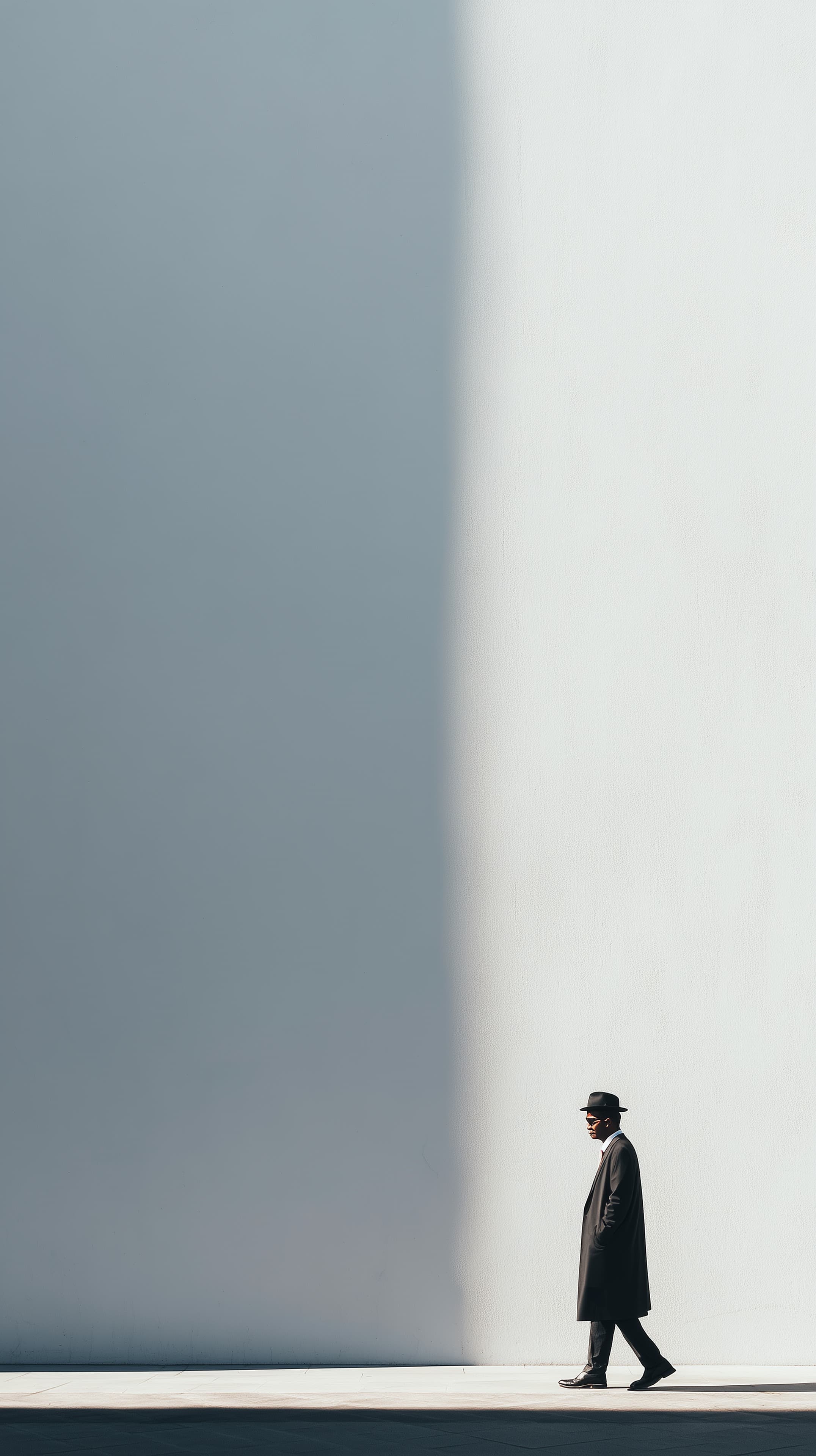 Minimalist Street Portrait: Man in Coat by White Wall - High Resolution architectural-silhouette Wallpaper for Mobile and Desktop
